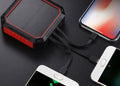 Solar power bank charging multiple smartphones on a dark surface